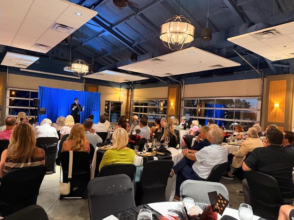 Comedy magic show in progress at the Cedar Creek Yacht Club with members seated at banquet tables.