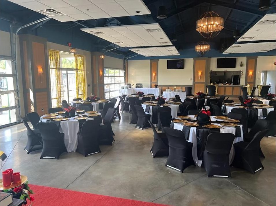 Cedar Creek Yacht Club banquet room set for the Supper Club with round tables, gold chargers and red centerpieces before guests arrived.