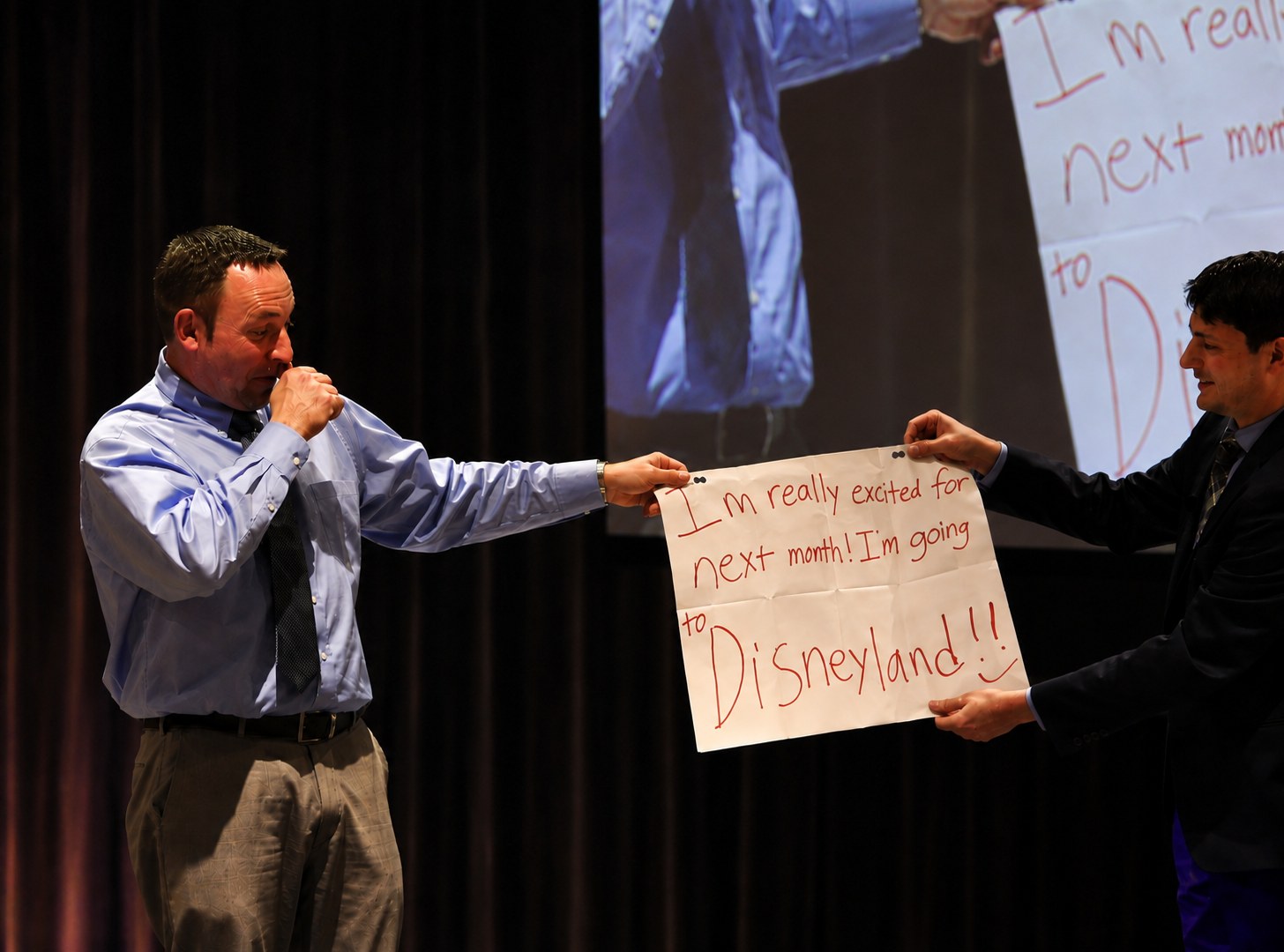 Corporate magician Josh Weidner revealing a written prediction on stage as the volunteer reacts