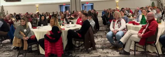 Guests seated at round tables watching a corporate holiday party magic show in St Louis