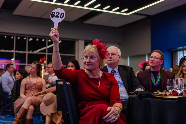 A donor raising her paddle during a fundraising gala