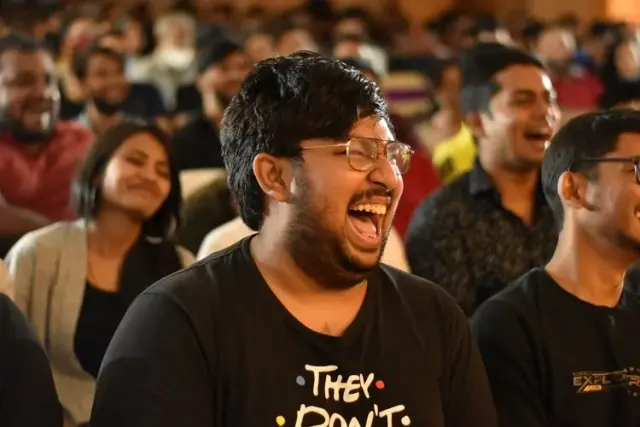 A packed crowd reacting during a comedy magic show