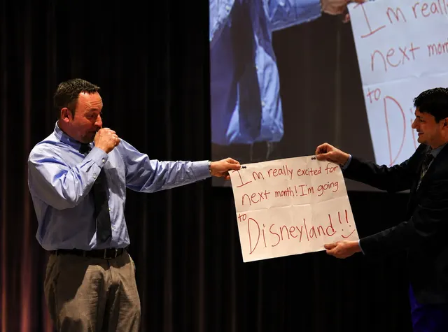 Corporate magician Josh Weidner revealing a written prediction on stage with a volunteer
