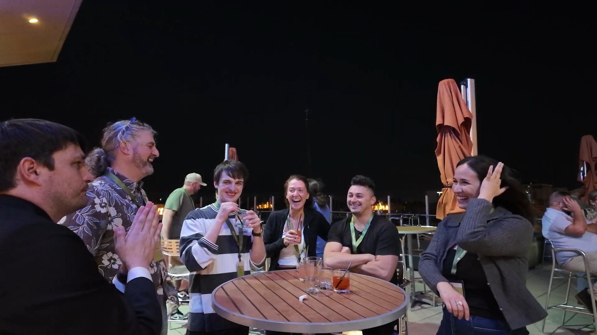Guests laughing together as a strolling magician performs close-up magic at an outdoor reception